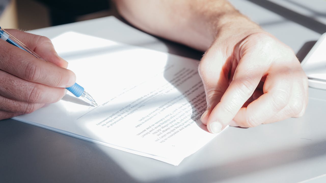 Mastering the First Impression: Your intriguing post title goes here Hands signing a contract with a blue pen, close-up view.