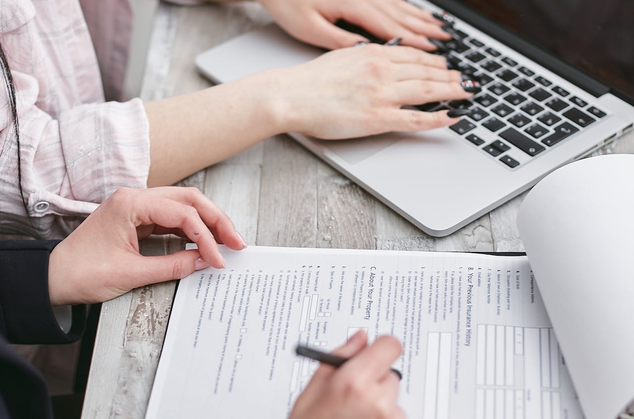 The Art of Drawing Readers In: Your attractive post title goes here Close-up of hands typing on a laptop and reviewing business documents, focused on finance and legal tasks.