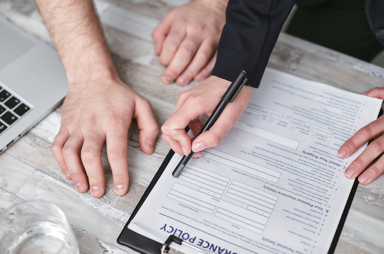 Crafting Captivating Headlines: Your awesome post title goes here Close-up image of two people signing an insurance policy document on a wooden desk.